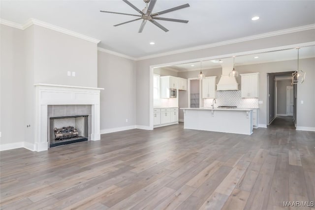 unfurnished living room featuring ceiling fan, a fireplace, ornamental molding, and hardwood / wood-style flooring