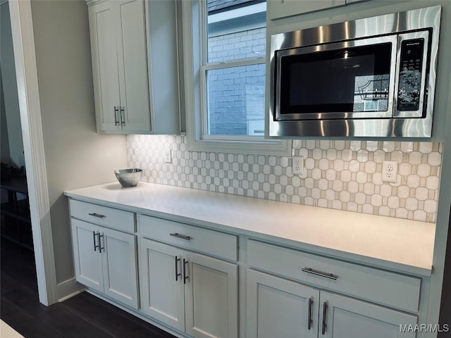 kitchen featuring white cabinets, dark hardwood / wood-style floors, stainless steel microwave, and backsplash