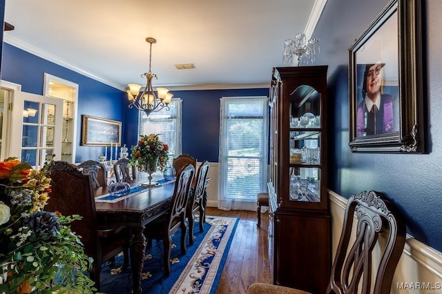 dining area featuring dark hardwood / wood-style floors, crown molding, and an inviting chandelier