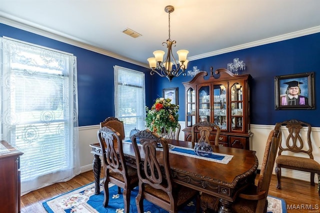 dining room featuring wood-type flooring, ornamental molding, and a chandelier