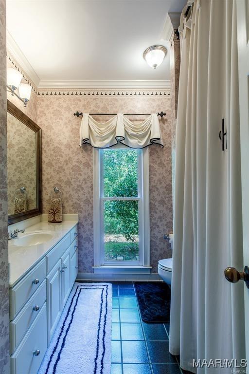 bathroom with toilet, vanity, tile patterned floors, and ornamental molding