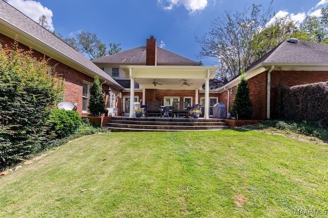 back of property with ceiling fan and a yard