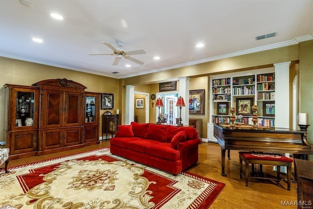 living area with ceiling fan, light wood-type flooring, crown molding, and decorative columns