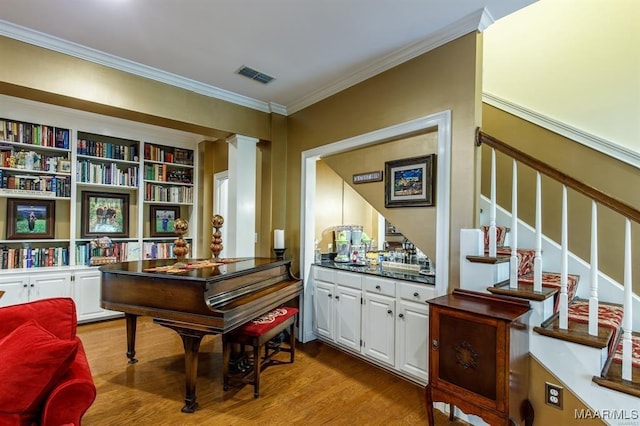 miscellaneous room featuring ornate columns, crown molding, and light hardwood / wood-style flooring