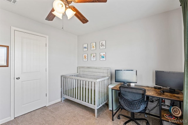 carpeted bedroom featuring a nursery area and ceiling fan