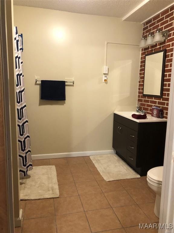 bathroom with tile patterned flooring, vanity, a textured ceiling, and toilet