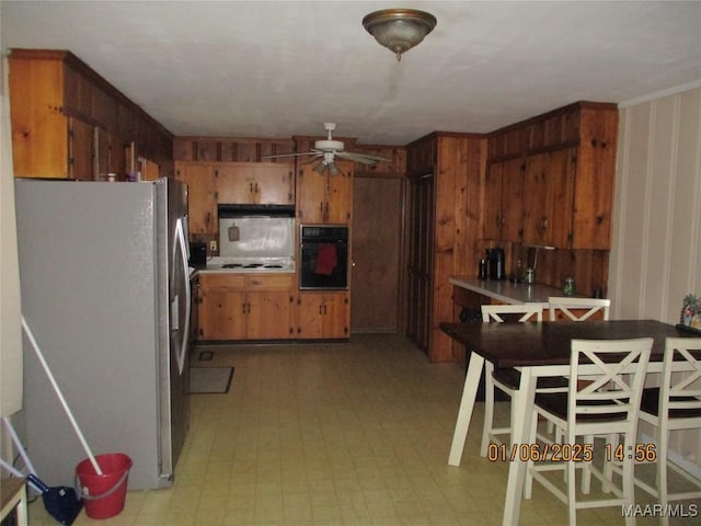 kitchen featuring ceiling fan, oven, stainless steel fridge, and white stovetop