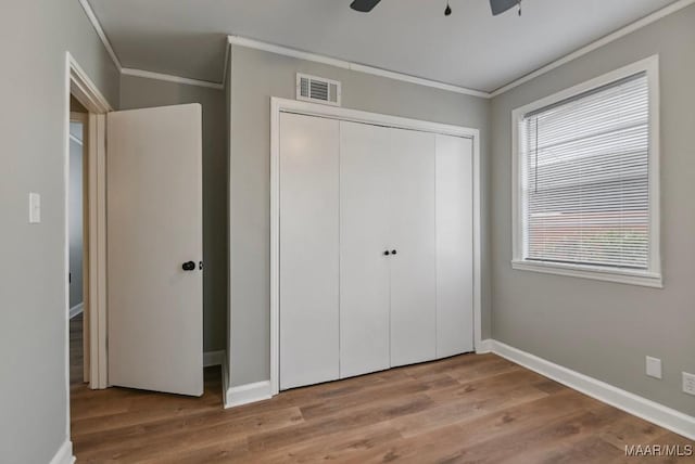 unfurnished bedroom featuring ceiling fan, light hardwood / wood-style floors, multiple windows, and a closet