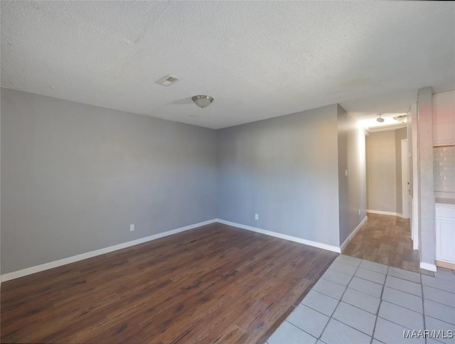 unfurnished room featuring wood-type flooring and a textured ceiling