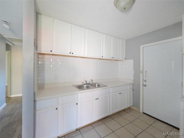 kitchen featuring white cabinets, decorative backsplash, light tile patterned floors, and sink