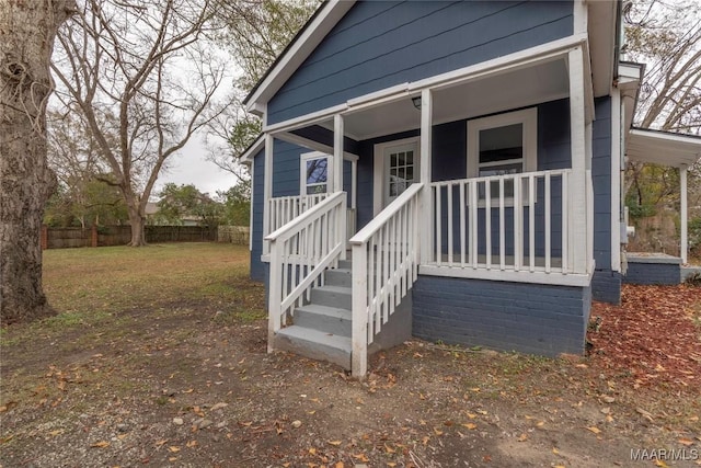 property entrance with a porch and a lawn