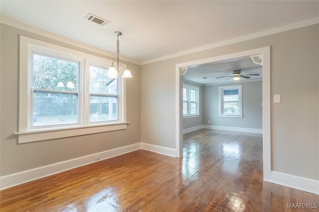 empty room featuring ceiling fan with notable chandelier, hardwood / wood-style flooring, and crown molding