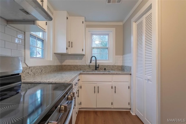 kitchen featuring light stone countertops, extractor fan, sink, white cabinetry, and stainless steel range with electric cooktop