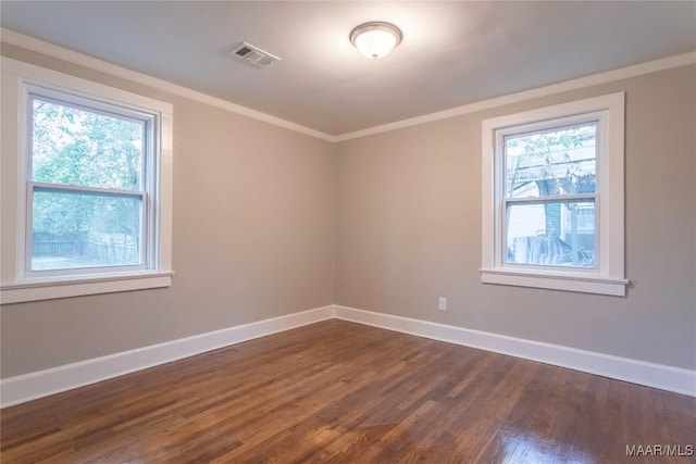 empty room with dark hardwood / wood-style floors, a wealth of natural light, and ornamental molding