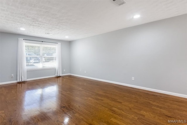 unfurnished room with a textured ceiling and hardwood / wood-style flooring