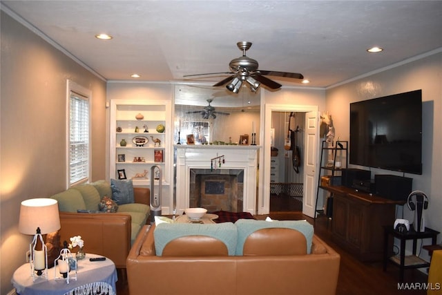 living room with built in shelves, dark hardwood / wood-style flooring, ceiling fan, and ornamental molding