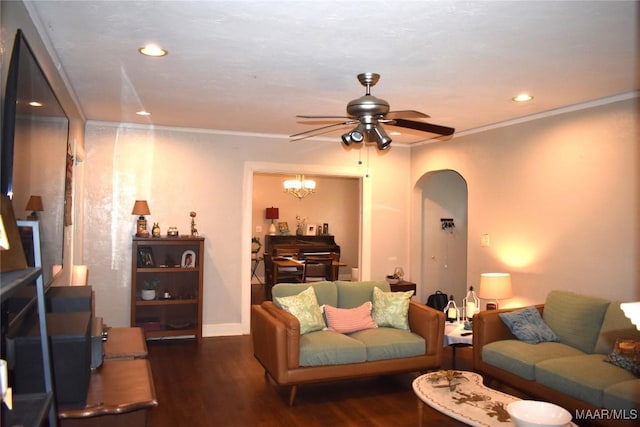 living room featuring dark wood-type flooring, ceiling fan with notable chandelier, and ornamental molding