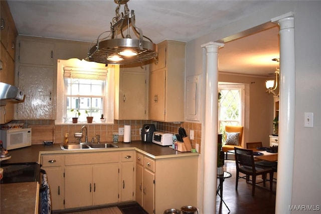 kitchen featuring plenty of natural light, tasteful backsplash, sink, and decorative columns