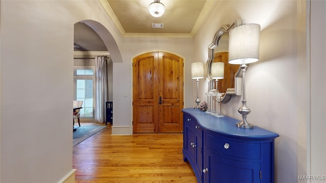 entryway with light wood-type flooring and crown molding