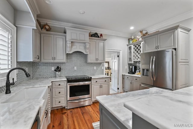 kitchen with sink, stainless steel appliances, tasteful backsplash, light hardwood / wood-style flooring, and gray cabinets