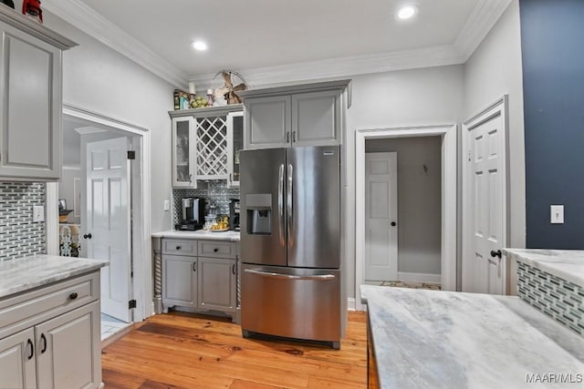 kitchen with tasteful backsplash, crown molding, light hardwood / wood-style flooring, stainless steel fridge with ice dispenser, and gray cabinets