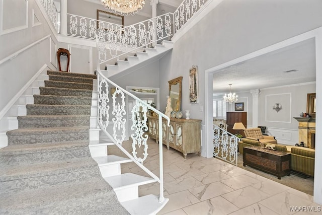 stairs featuring a chandelier, a high ceiling, and ornamental molding