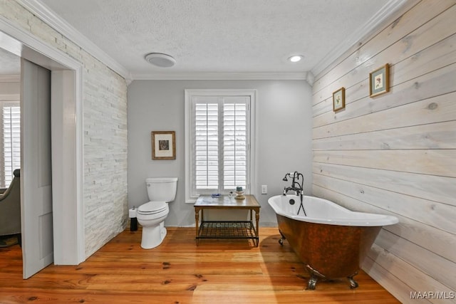 bathroom with hardwood / wood-style floors, toilet, ornamental molding, a textured ceiling, and a tub