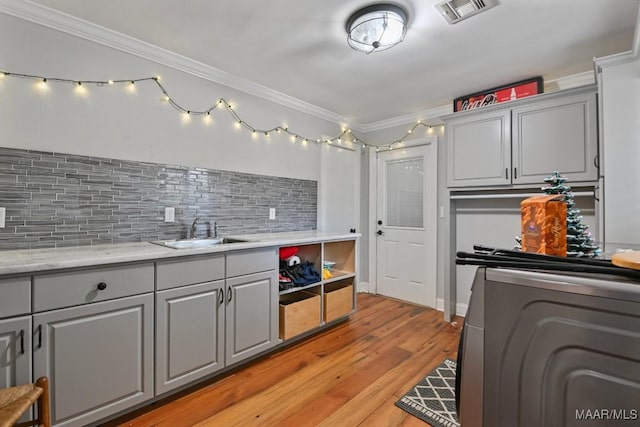 kitchen featuring gray cabinets, crown molding, sink, and washer / dryer