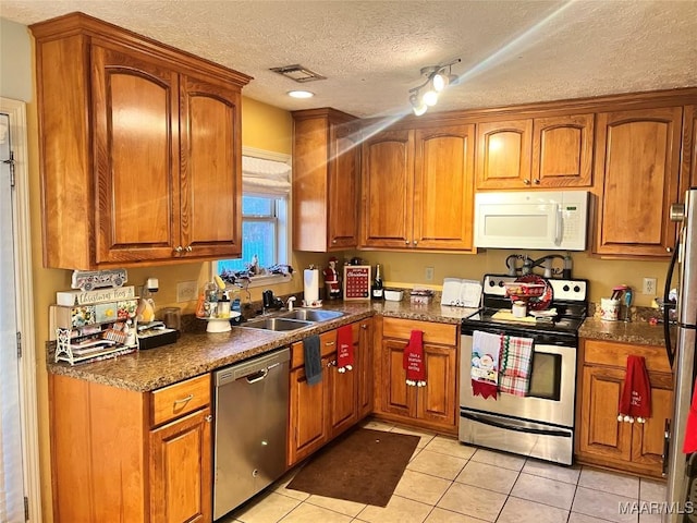 kitchen with a textured ceiling, light tile patterned flooring, sink, and appliances with stainless steel finishes