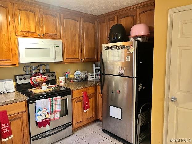 kitchen featuring a textured ceiling, stainless steel appliances, and light tile patterned flooring