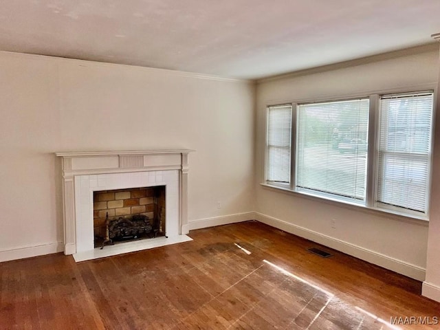 unfurnished living room featuring a fireplace, dark wood-type flooring, and ornamental molding