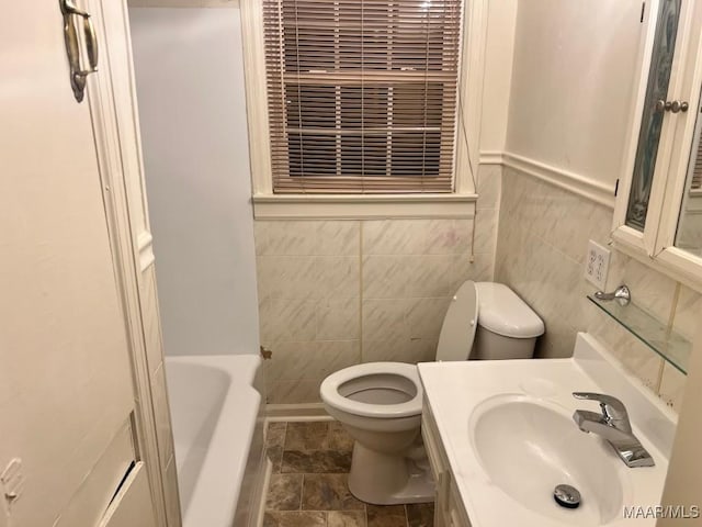 bathroom with a bathtub, vanity, tile walls, and toilet