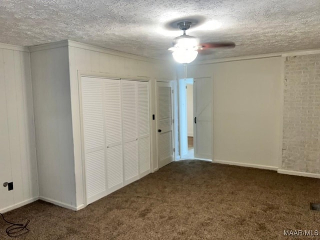 unfurnished bedroom featuring a textured ceiling, dark carpet, and ceiling fan