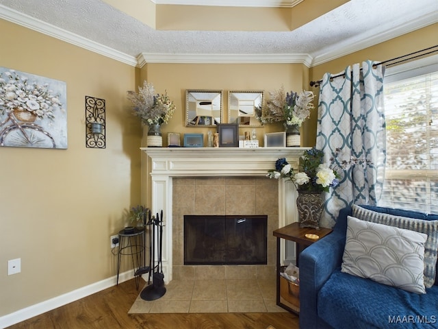 sitting room featuring hardwood / wood-style floors, crown molding, a tile fireplace, and a textured ceiling