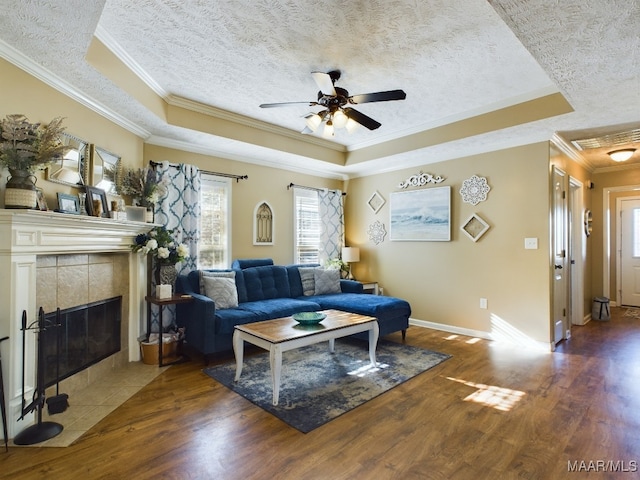 living room featuring a tray ceiling, ceiling fan, dark wood-type flooring, and ornamental molding