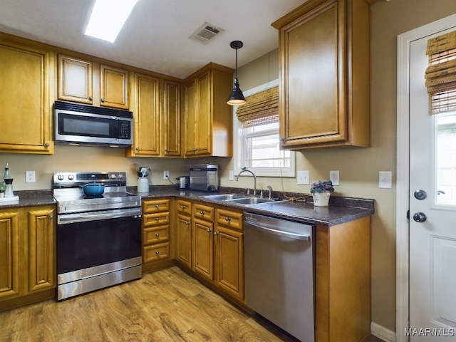 kitchen featuring pendant lighting, sink, stainless steel appliances, and light hardwood / wood-style flooring