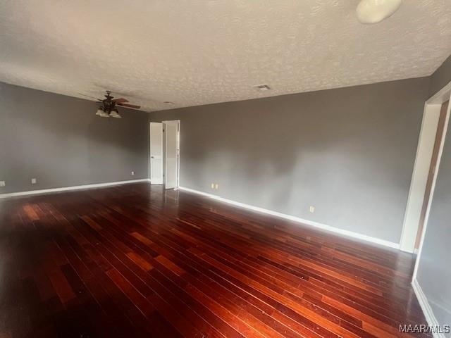 empty room with ceiling fan, dark hardwood / wood-style flooring, and a textured ceiling