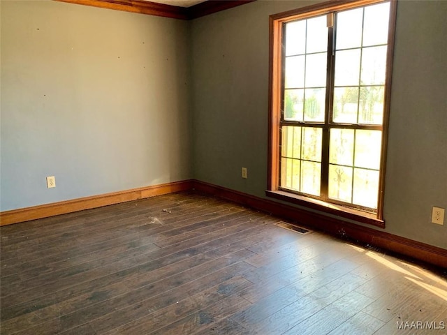 empty room with dark hardwood / wood-style floors and crown molding