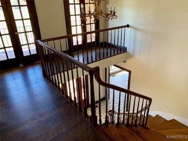 stairway featuring hardwood / wood-style floors, a notable chandelier, and french doors