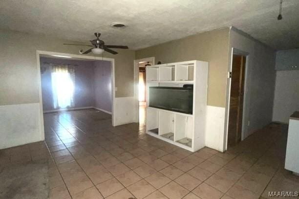 unfurnished living room featuring tile patterned floors and ceiling fan