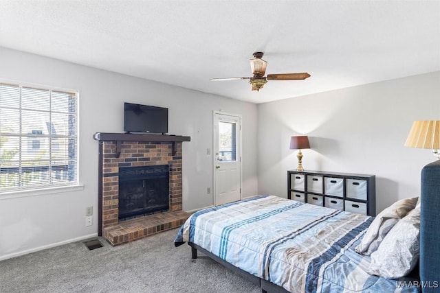 carpeted bedroom with ceiling fan and a fireplace