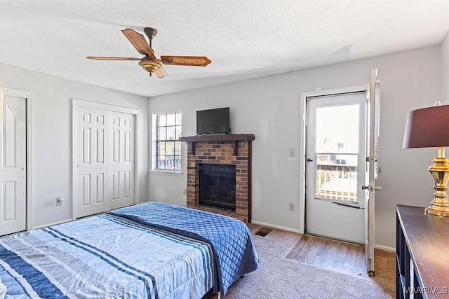 carpeted bedroom with a textured ceiling, ceiling fan, and a fireplace