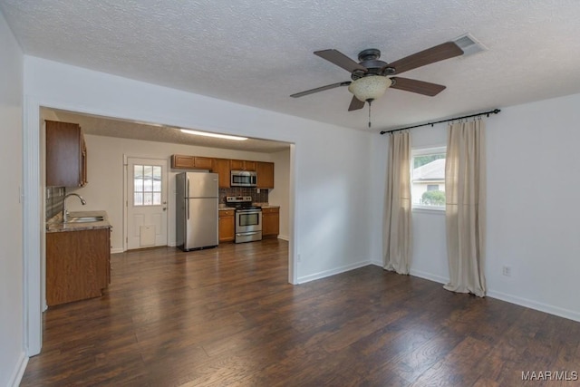 unfurnished living room with ceiling fan, sink, dark wood-type flooring, and a textured ceiling