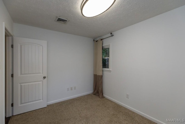 spare room with a textured ceiling and light colored carpet