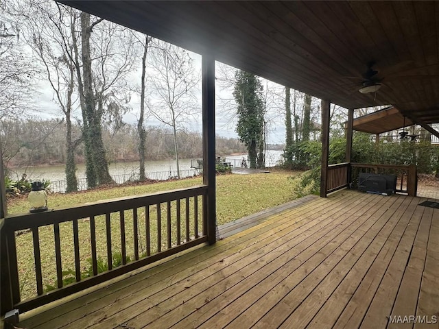 wooden terrace with a yard, a water view, and ceiling fan