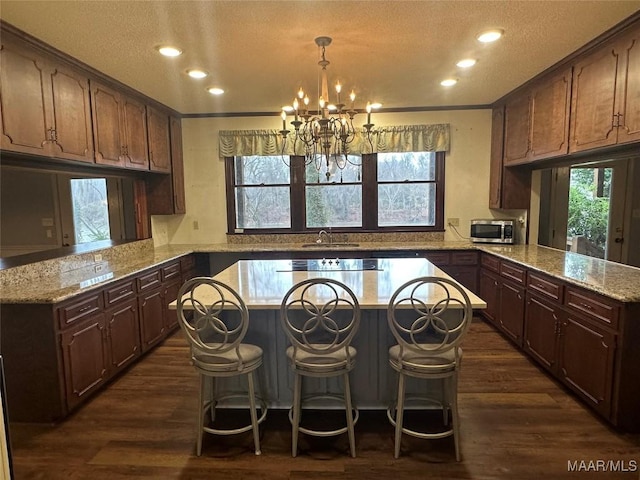 kitchen featuring sink, a center island, dark wood-type flooring, kitchen peninsula, and a chandelier