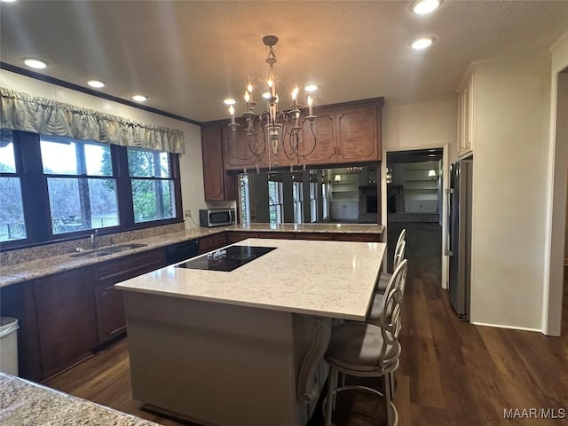 kitchen with a kitchen island, sink, appliances with stainless steel finishes, and dark wood-type flooring