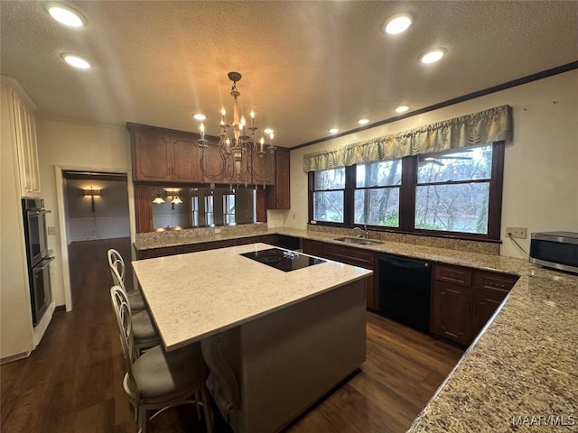 kitchen with a center island, black appliances, crown molding, sink, and dark brown cabinetry