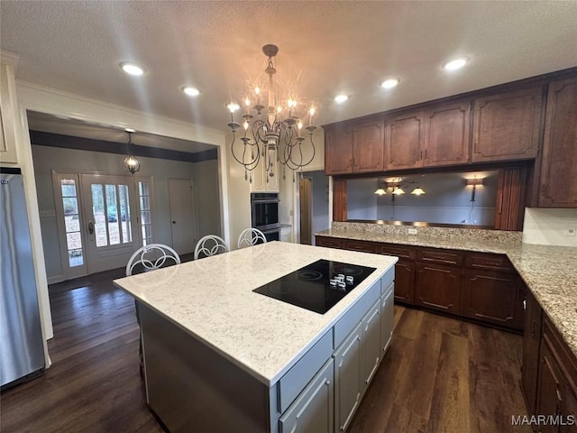 kitchen featuring appliances with stainless steel finishes, dark brown cabinetry, dark wood-type flooring, pendant lighting, and a center island