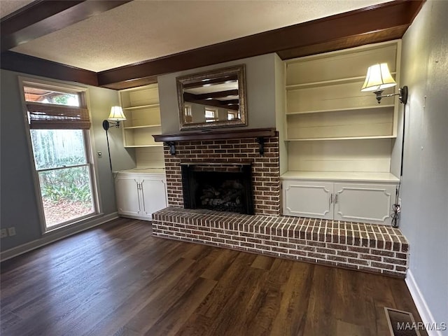 unfurnished living room featuring built in shelves, a fireplace, dark wood-type flooring, and a textured ceiling